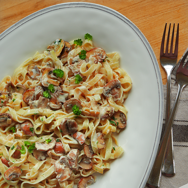 Pasta mit Champignons mit Gabeln und Serviette