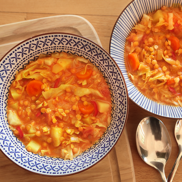 Spitzkohl-Curry in zwei Schüsseln auf einen Holztisch