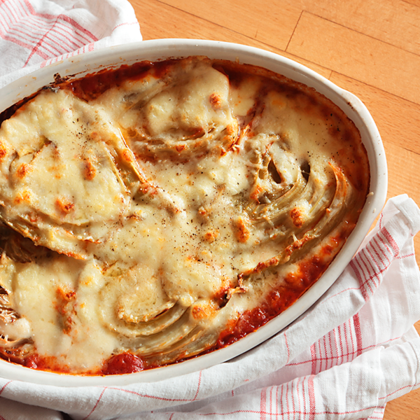 Fenchel-Parmigiana in einer Auflaufform mit Tuch auf Holztisch