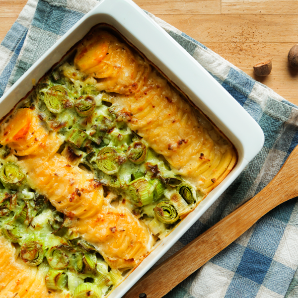 Lauch-Kartoffel-Gratin mit Holzlöffel auf einem Holztisch