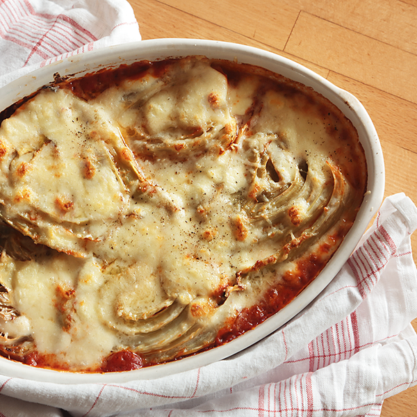 Fenchel-Parmigiana in einer Auflaufform mit Tuch auf Holztisch