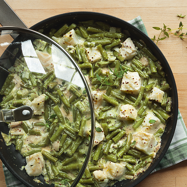 Grüne Bohnenpfanne mit Fisch auf einem Holzbrett