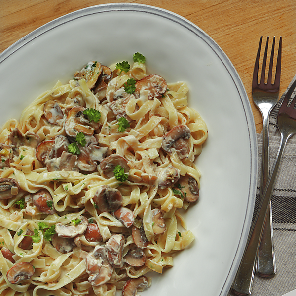 Pasta mit Champignons mit Gabeln und  Serviette